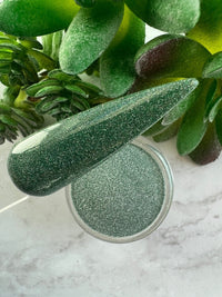 Photo shows swatch of Dipnotic Nails Mirage Dark Green Reflective Glitter Nail Dip Powder