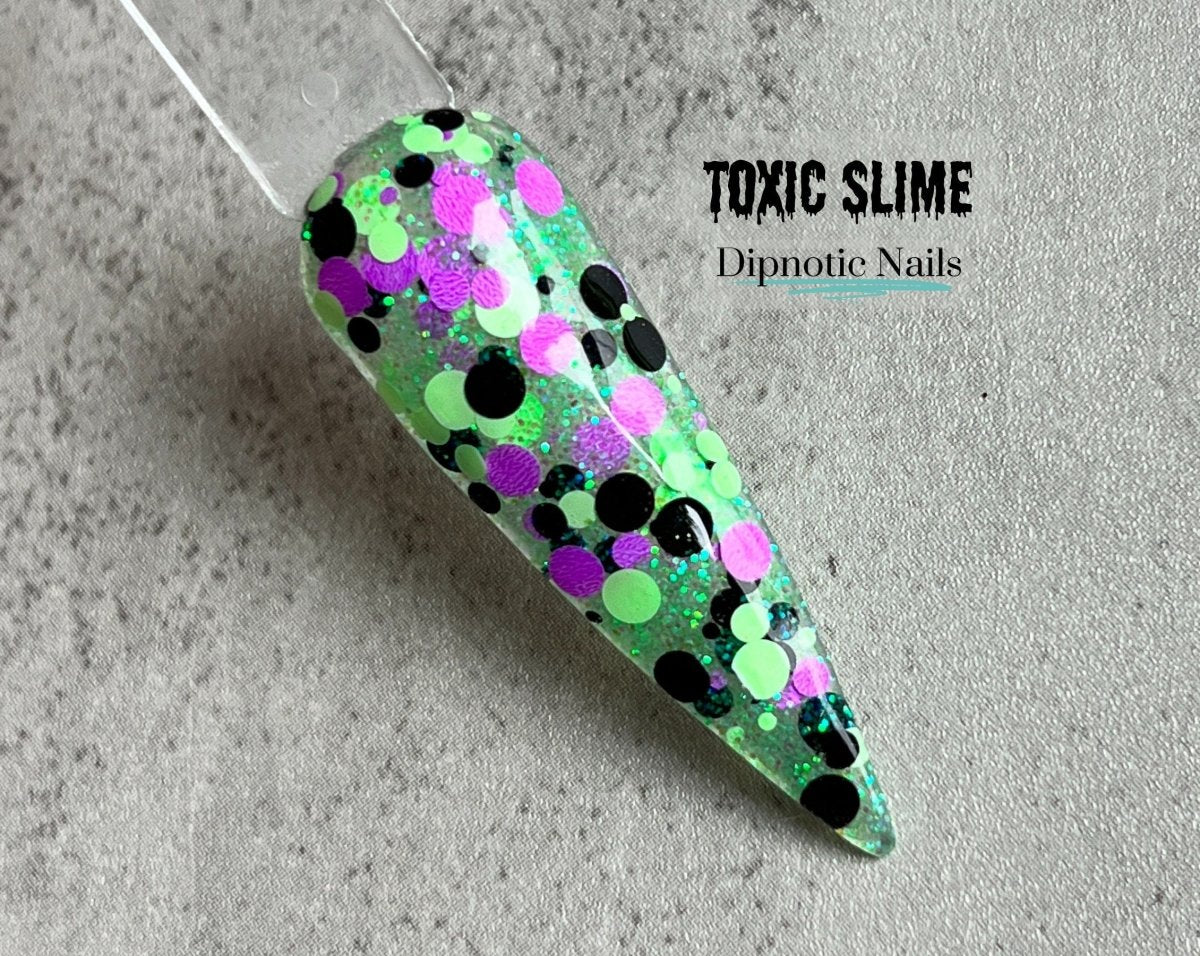 Photo shows swatch of Dipnotic Nails Toxic Slime Green, Purple, and Black Nail Dip Powder Halloween 2023 Collection